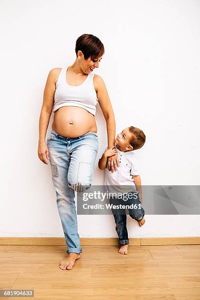 pregnant mother holding hand of little son - wooden floor white background stock pictures, royalty-free photos & images