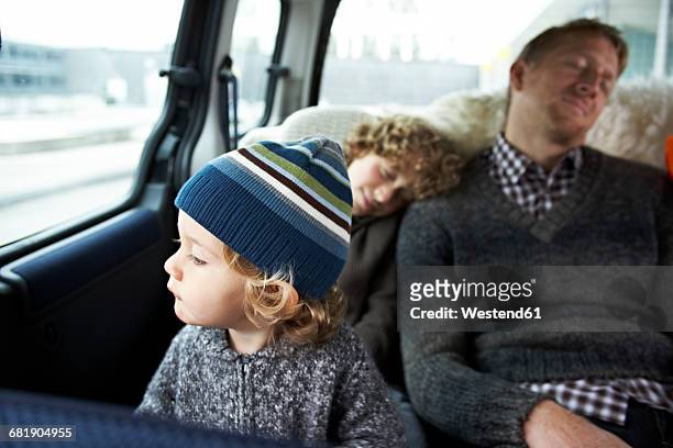 sleeping father sitting in car on back seat with his sons - auto schlafen stock-fotos und bilder