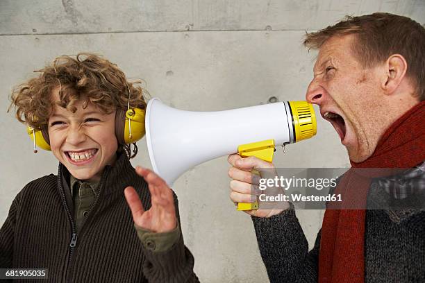 father and son screaming at each other with magaphone - orejeras fotografías e imágenes de stock