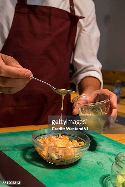 man pouring vinaigrette with a spoon in a bowl with peruvian ceviche - ceviche stock pictures, royalty-free photos & images