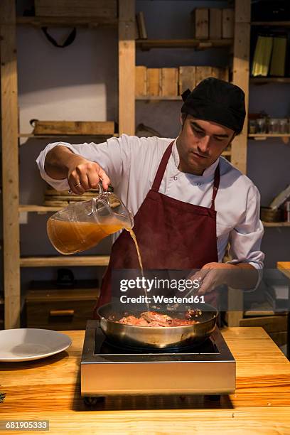 man pouring broth on beef cheeks in a pan with sauteed vegetables - pouring sauce stock pictures, royalty-free photos & images