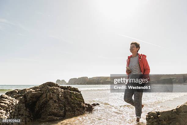 mature woman wading in the sea - une seule femme d'âge mûr photos et images de collection