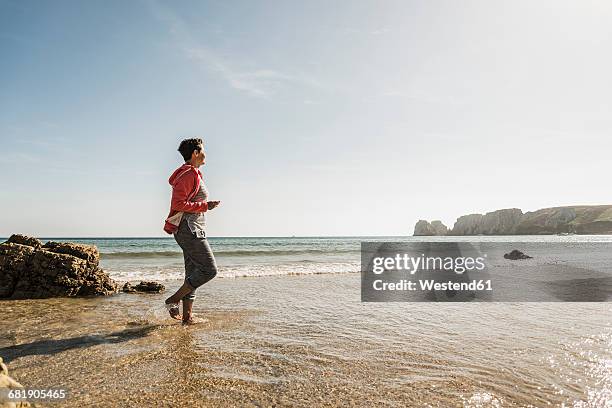 mature woman wading in the sea - mature woman in water stock pictures, royalty-free photos & images