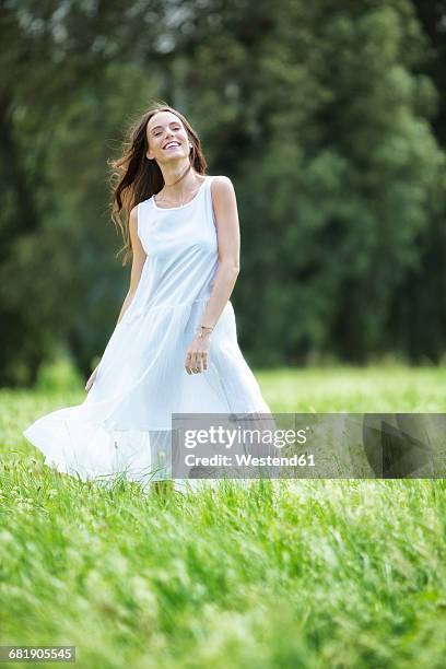 happy woman wearing white summer dress standing on a meadow - sommerkleid stock-fotos und bilder