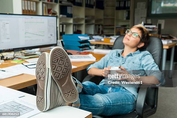 woman sitting in office with feet up, taking a break - feet up stock pictures, royalty-free photos & images