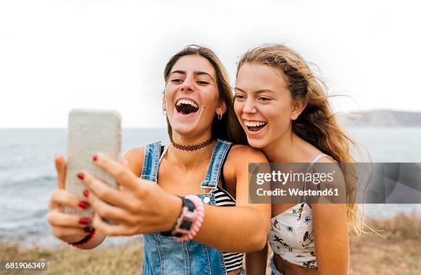 two best friends taking selfie with smartphone at the coast - beach girl stock pictures, royalty-free photos & images