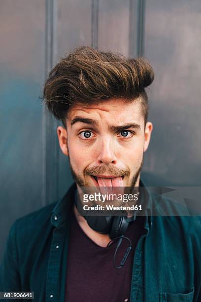 portrait of young man sticking out tongue - sticking out tongue stock pictures, royalty-free photos & images