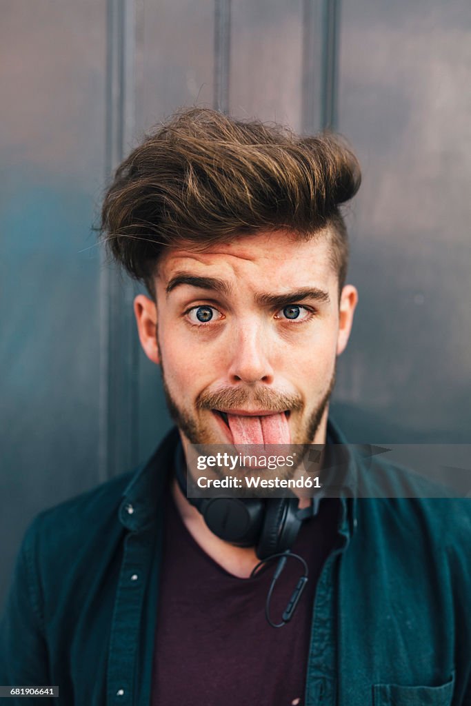 Portrait of young man sticking out tongue