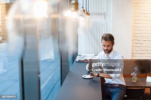 businessman in a cafe checking the time - bistro lights stock pictures, royalty-free photos & images