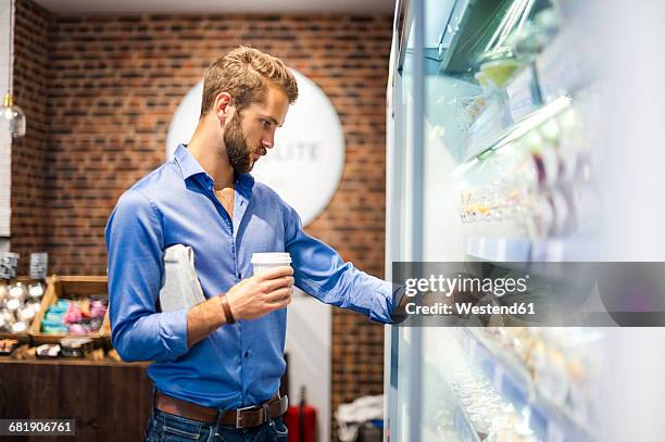 young man choosing food from cooling shelf in a coffee shop - convenient store 個照片及圖片檔