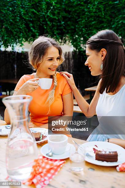two young women drinking coffee at outdoor cafe - heuriger stock-fotos und bilder