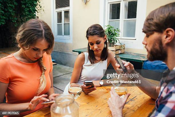 friends using cell phones and drinking spritzer at outdoor pub - spritzer stock pictures, royalty-free photos & images