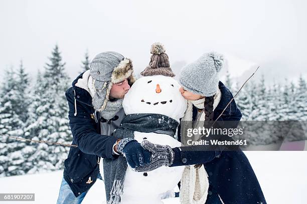 couple kissing snowman - making a snowman stock pictures, royalty-free photos & images