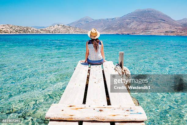 greece, cyclades islands, amorgos, woman sitting on the edge of a wooden pier, nikouria island - grekiska övärlden bildbanksfoton och bilder