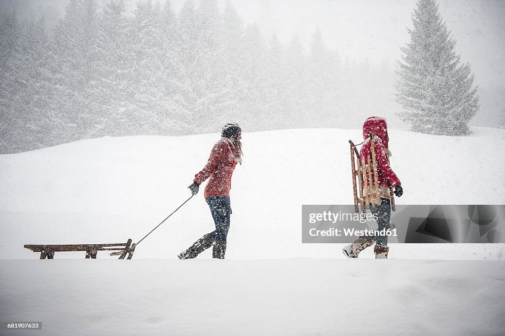 Two young women with sledges in heavy snowfall