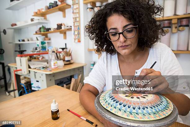 woman painting a ceramic plate with a brush - accompagnement professionnel photos et images de collection