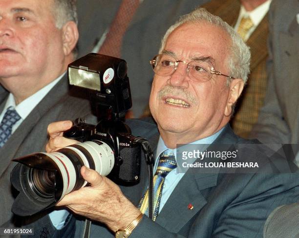 Syrian Defence Minister Gen. Mustafa Tlass holds an AFP photo-journalist's camera during a lecture for Palestinian poet Samih al-Kassem 18 November...