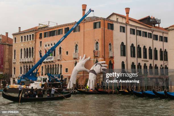 Workers finish to prepare the exhibition 'SUPPORT' by Lorenzo Quinn, during the 57th Biennale Arte on May 11, 2017 in Venice, Italy. The 57th...