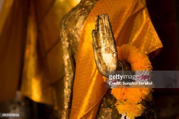 the hand of miniature phra lokanad with flower garland - buddha hands stock-fotos und bilder
