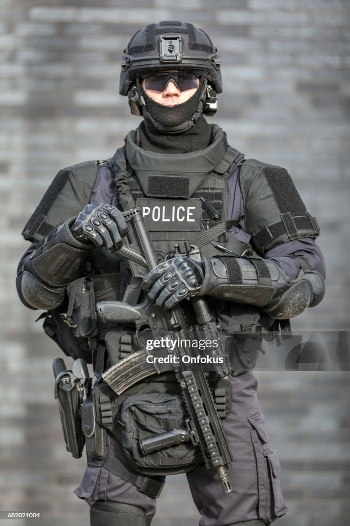 Oficial de policía SWAT contra pared de ladrillos