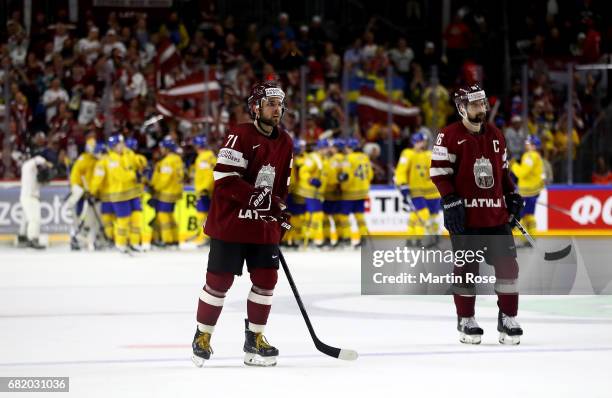 Roberts Bukarts and team mate Kaspars Daugavins of Latvia lookdejected after the 2017 IIHF Ice Hockey World Championship game between Sweden and...