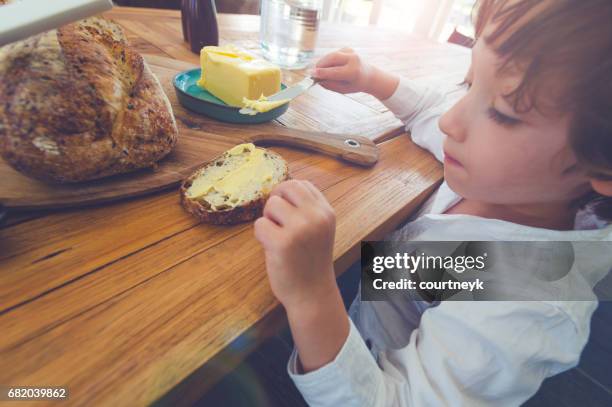 niño buttering su pan. - untar de mantequilla fotografías e imágenes de stock