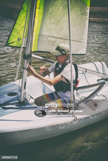 tiener jongen leren zeil en stropdas knopen op kleine zeilboot - spinnaker stockfoto's en -beelden