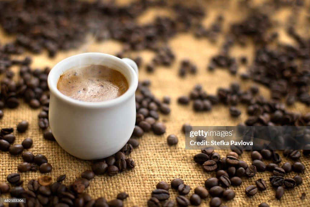Coffee drink in cup on coffee beans background.