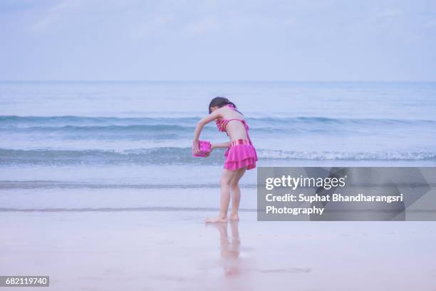 toddler girl rinsing the sand toy - suphat bhandharangsri stock pictures, royalty-free photos & images