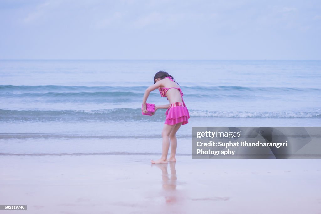Toddler girl rinsing the sand toy