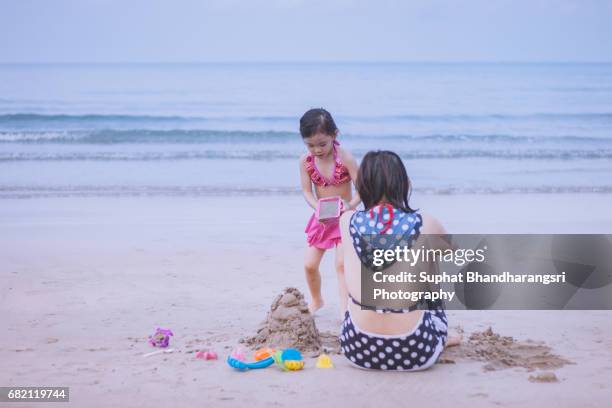 daughter building sand castle with her mother - suphat bhandharangsri stock pictures, royalty-free photos & images