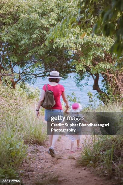 mother & daughter walking down the hill to the sea - suphat bhandharangsri stock pictures, royalty-free photos & images