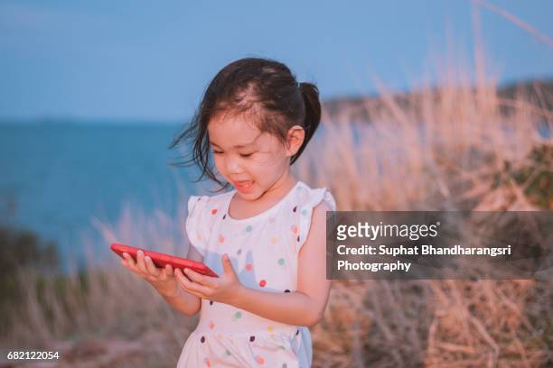 toddler girl holding a smartphone at the hill - suphat bhandharangsri stock pictures, royalty-free photos & images