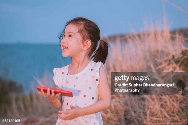 toddler laughing at the photos she sees on a smartphone - suphat bhandharangsri stock pictures, royalty-free photos & images