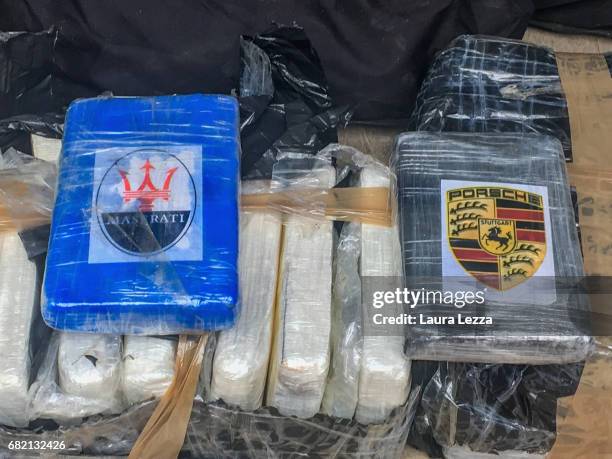 Some bricks of cocaine with Porsche and Maserati cars logos are displayed on May 11, 2017 in Livorno, Italy. Black Backpacks roped together and...