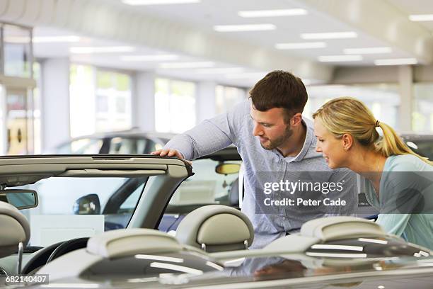 couple looking at car for sale in showroom - car sale stockfoto's en -beelden