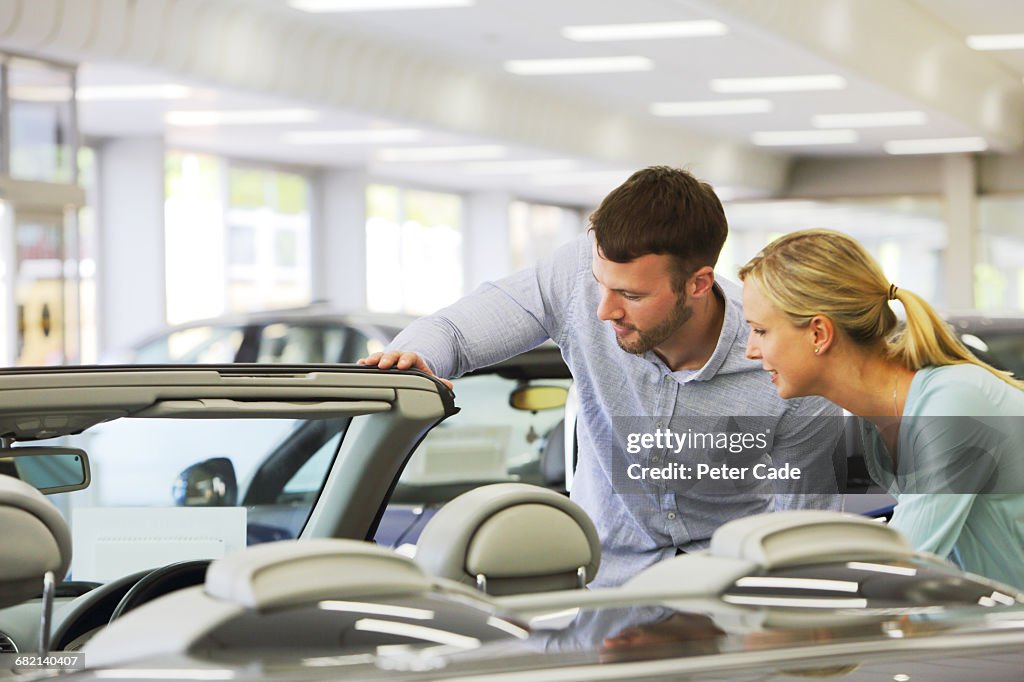 Couple looking at car for sale in showroom