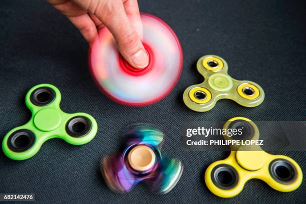 Person poses while holding a hand spinner, a new spinning-top toy, on May 11, 2017 in Paris. / AFP PHOTO / PHILIPPE LOPEZ