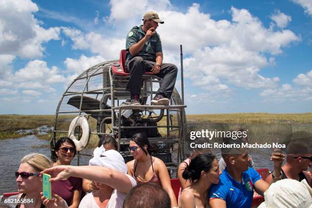 Tourists and guide in airboat exploring the Everglades. The Everglades is a natural region of tropical wetlands in the southern portion of the U.S....