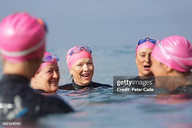 woman chatting in sea after swim - small group of people outside stock pictures, royalty-free photos & images