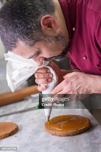 italian pastry making patisserie baking confectioner: using sac a poche for decorating a sachertorte with apricot jam - sachertorte stock pictures, royalty-free photos & images