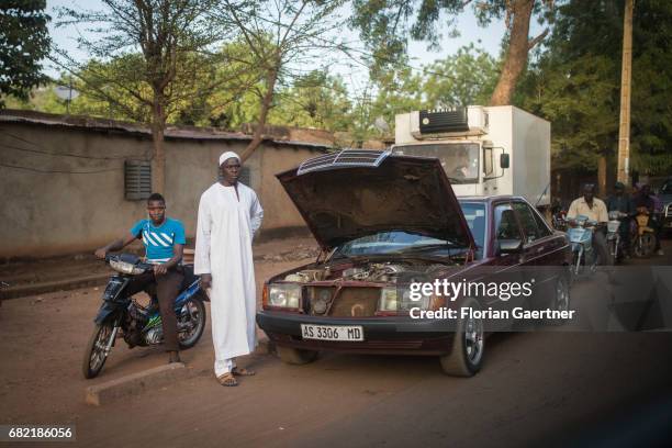 April 07: An African man stands next to his broken car. Breakdown on a road on April 07, 2017 in Bamako, Mali.