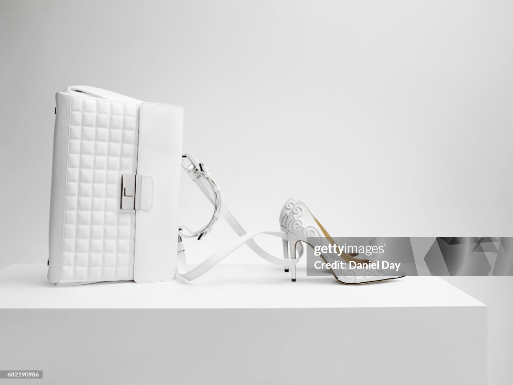A white bag with white shoes in the form of Cinderella's coach
