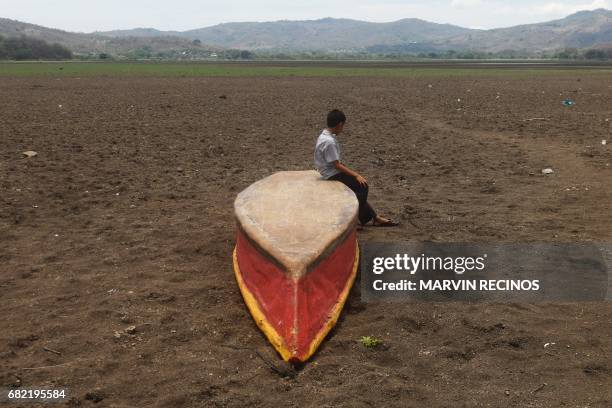 Boy sits on an abandoned boat on what is left of Lake Atescatempa, which has dried up due to drought and high temperatures, in Atescatempa, 174 km...
