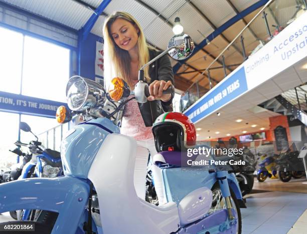 young woman stood with motorbike and helmet in showroom - buying a bike bildbanksfoton och bilder