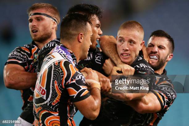 Aaron Gray of the Rabbitohs wtestles with Luke Brooks of the Tigers and James Tedesco of the Tigers during the round ten NRL match between the Wests...