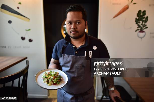 French chef Tomy Gousset holds a dish as he poses at his 'Tomy & Co' restaurant in Paris on May 11, 2017. / AFP PHOTO / CHRISTOPHE ARCHAMBAULT