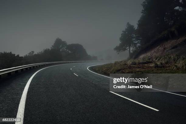 curved road on dark foggy day - straße kurve stock-fotos und bilder