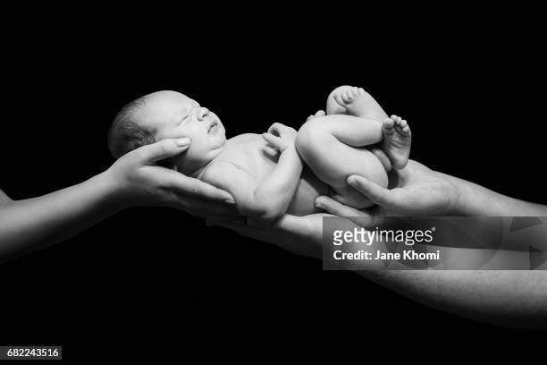 hands of father and mother holding newborn baby - position du foetus photos et images de collection