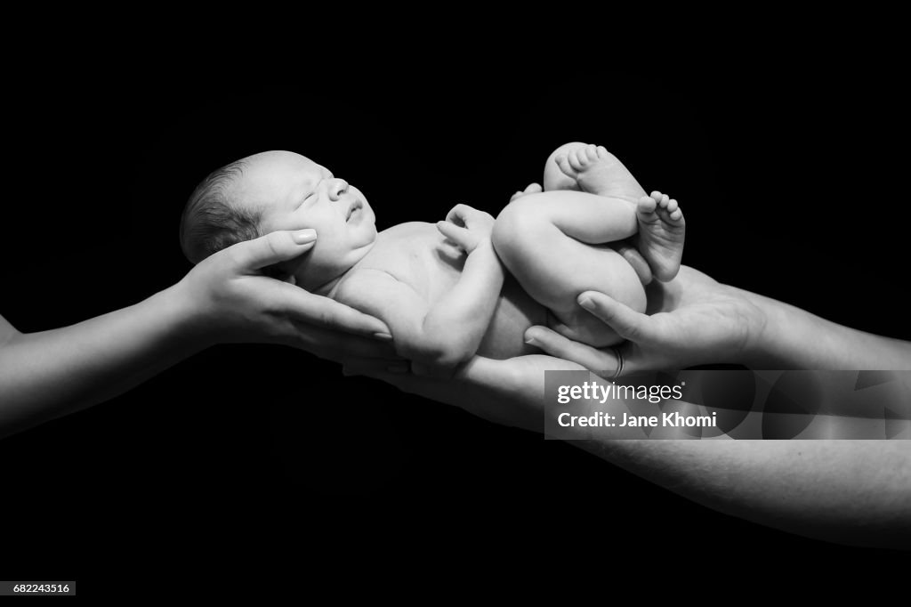 Hands of Father and Mother Holding Newborn Baby